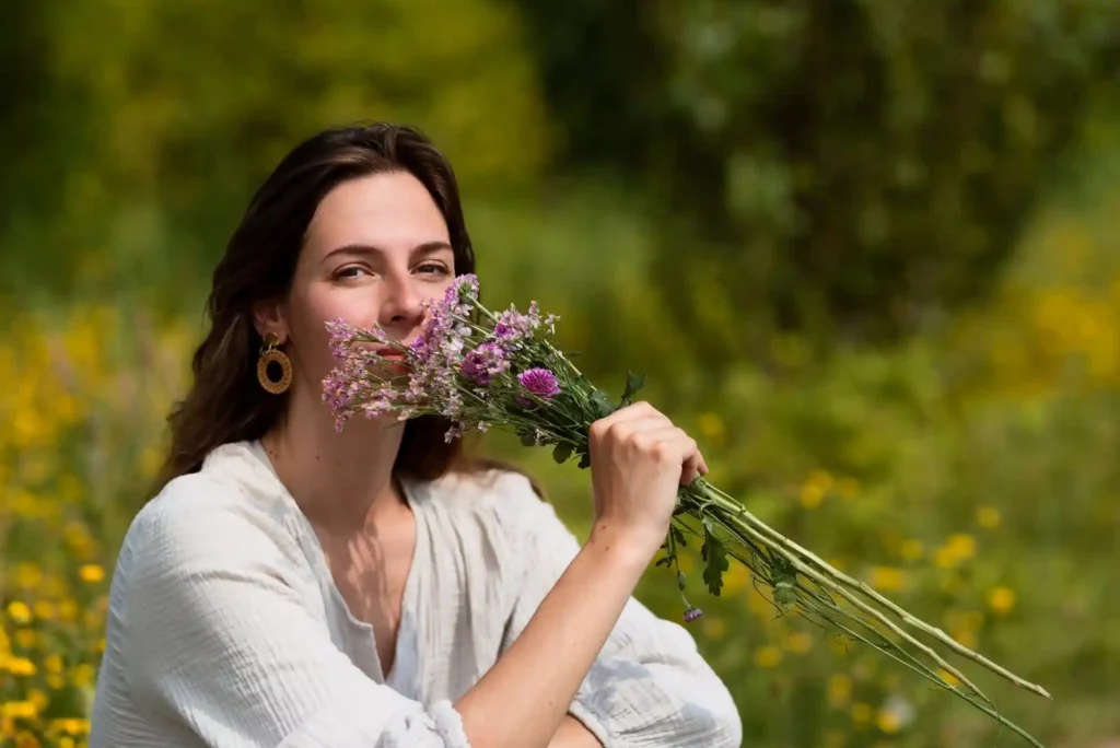 Anna Vlasic hält einen Strauß Wildblumen in der Natur und steht für einen achtsamen ökologischen Lifestyle
